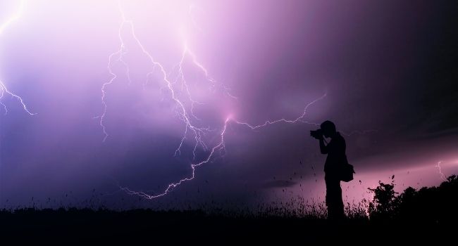 person taking photos of lightning at night
