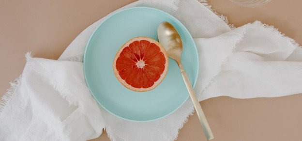 Image of orange on plate over white cloth